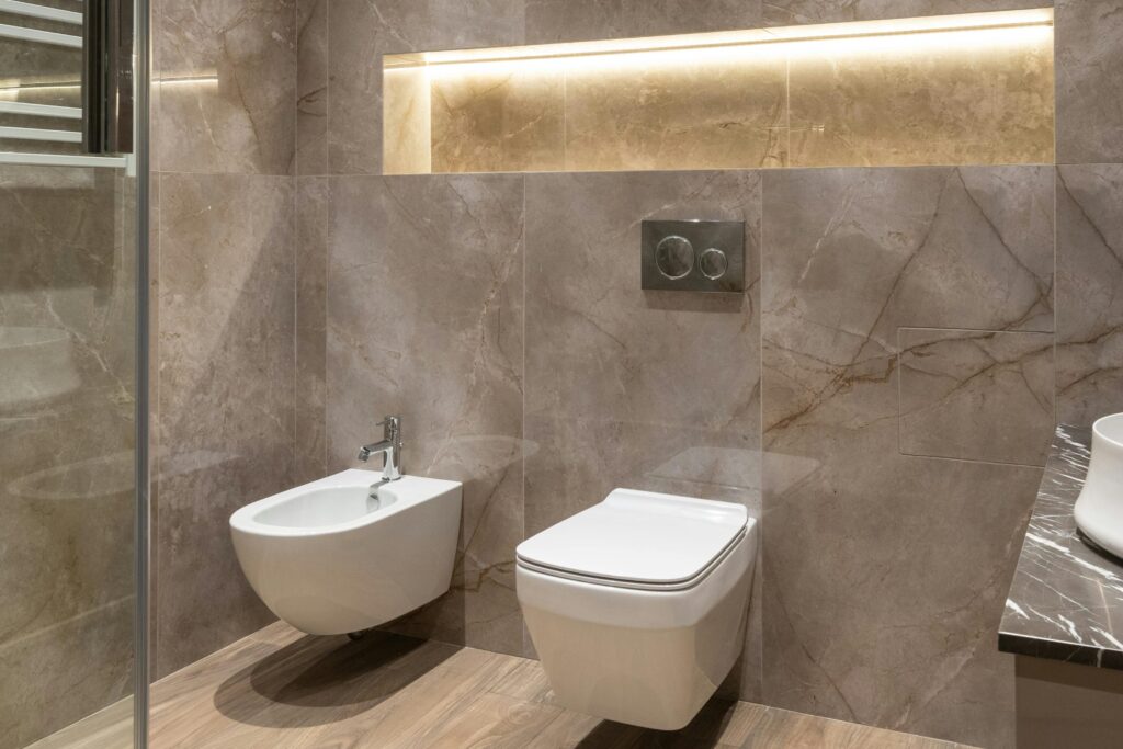 Glass shower cabin and ceramic sink with toilet bowl and bidet in spacious contemporary bathroom with shiny tiles and round mirrors. Quanto costa ristrutturare un bagno di 6 mq.