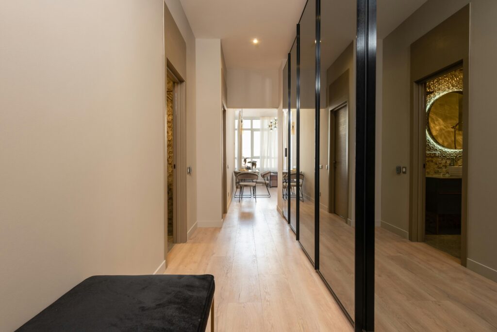 Interior of modern apartment with cabinets with mirrors in front of pouf near entrance in hallway