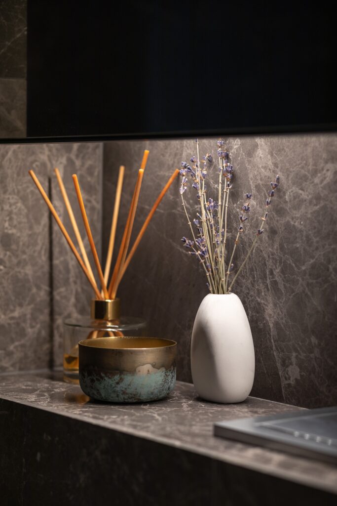 Minimalist decor with vase and aroma sticks on marble surface in warm lighting.