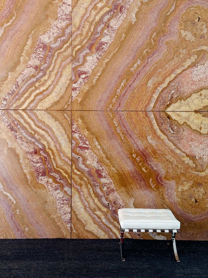 Stylish modern interior design featuring a marble wall and a classic chair in Barcelona, Grandi formati.