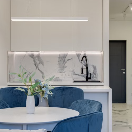 Contemporary kitchen design featuring blue chairs, round table, and marble elements, casa piccola