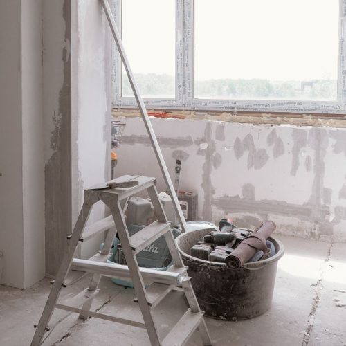 Sunlit room under renovation with tools and ladder, embodying modern DIY projects, intervento edilizio